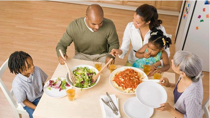 "Mother & father serving two children dinner at table