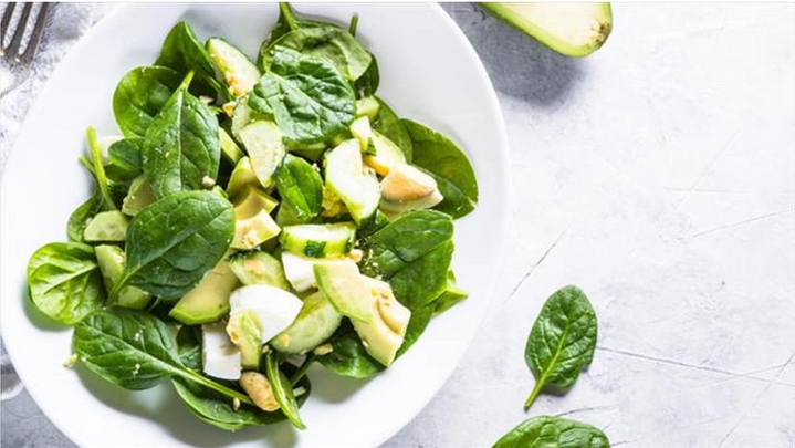 Seasonal Green Salad with Fresh Spinach & Avocado with napkin and fork.