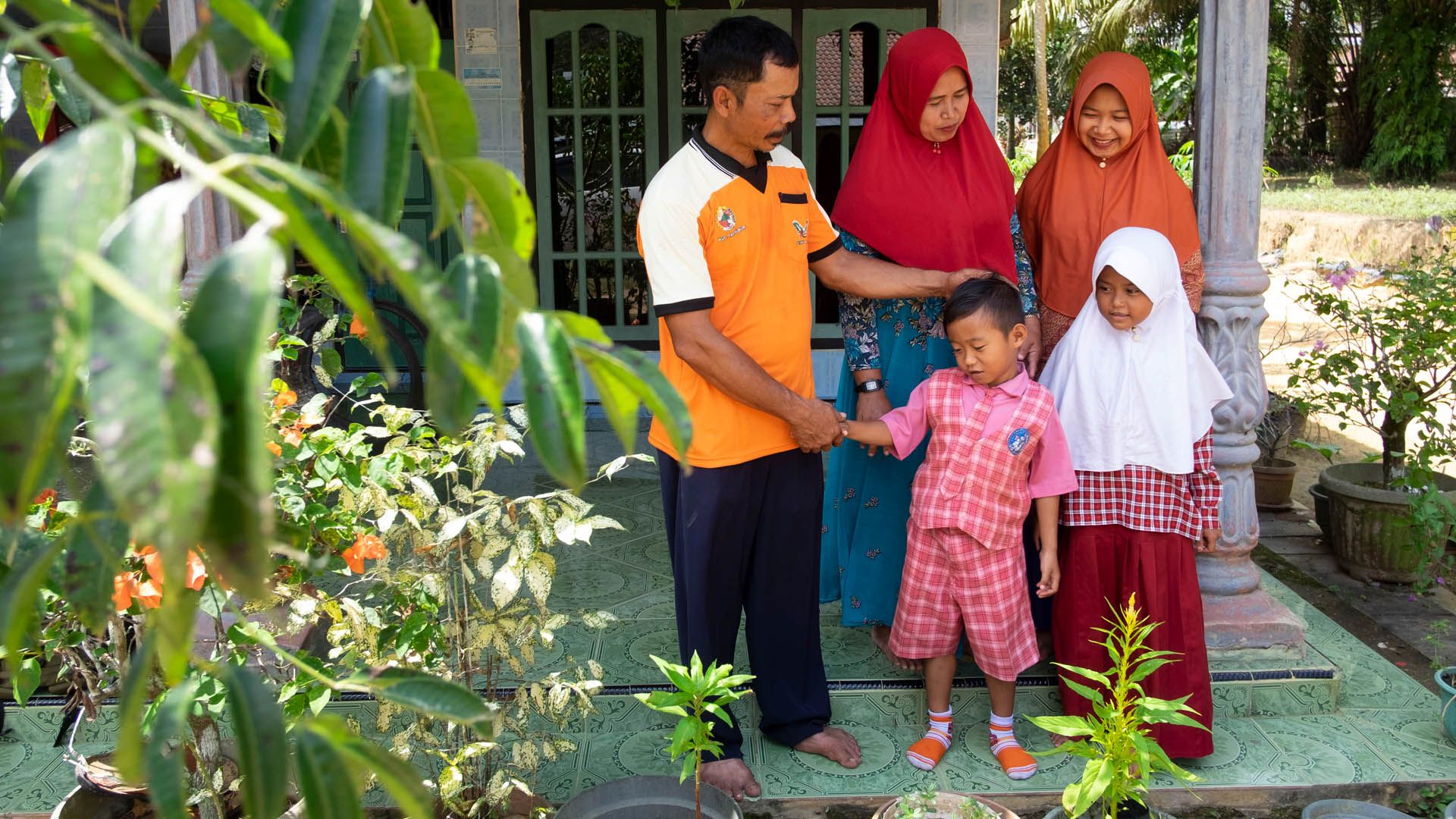Smallholder farmer’s family standing on the porch of their house.