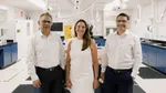 Three Unilever leaders stand side-by-side, looking at camera. Scientific R&D equipment is seen in the background.