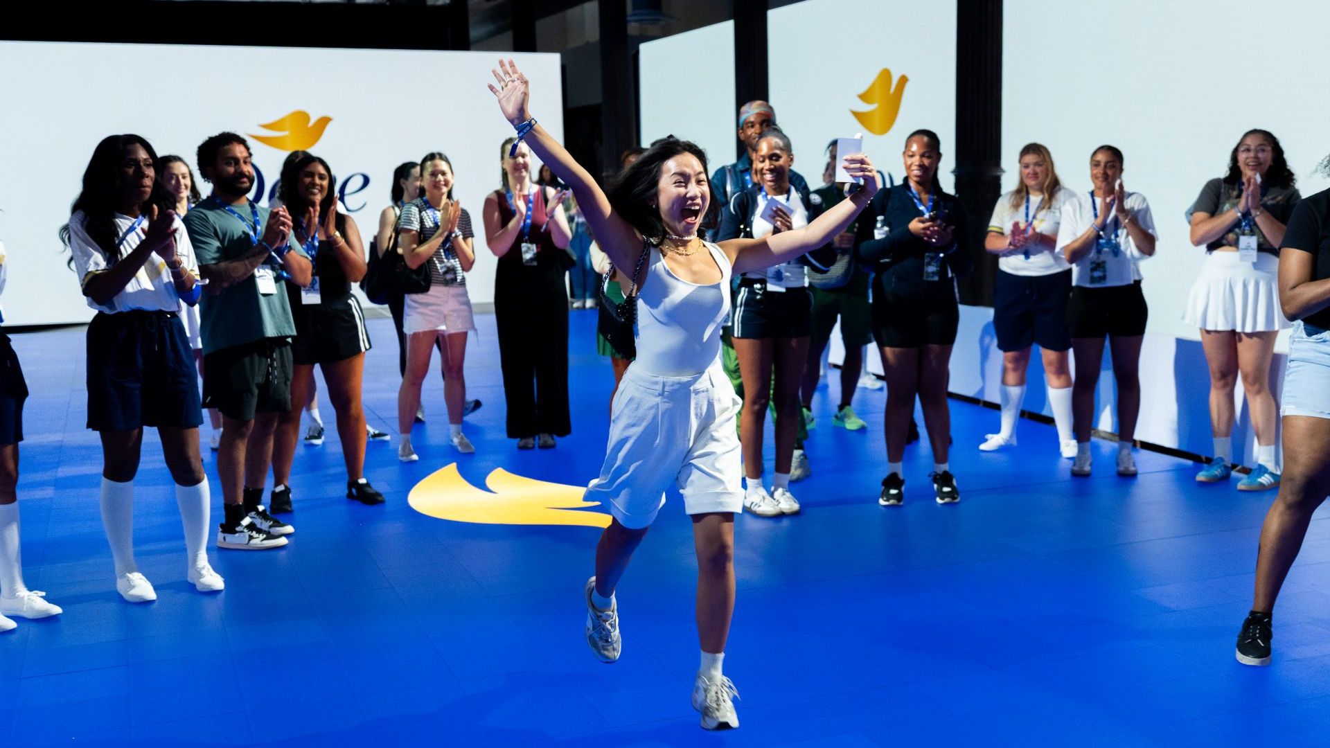 Women join a Dove choreography event at Unilever's House of Fresh. At the front a woman, hands aloft, smiles in delight.