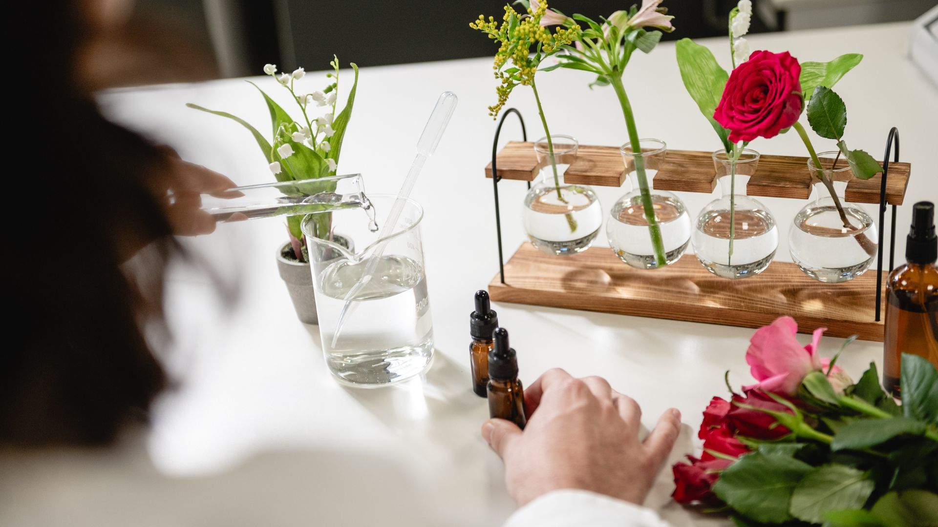 A scientist tests fragrance combinations in the lab. Pictured are roses, lily of the valley, vials and test tubes.