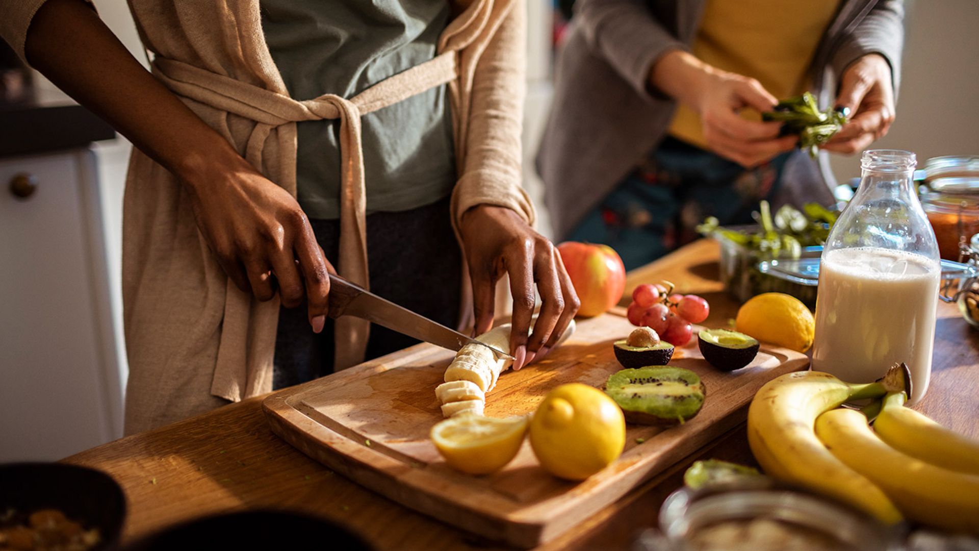 Close up shot of two pairs of hands preparing fruit and vegetables