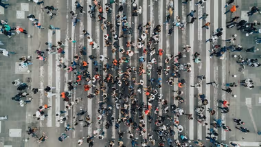Aerial view photograph of a large number of people crossing a road.
