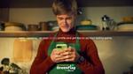 A still from Knorr’s Green Flag social influencer campaign shows a man in a green apron smiling as he looks at his phone .