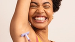 A smiling woman shaving her armpit
